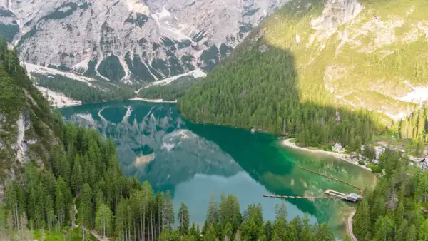 Un lago alpino dalle acque smeraldine, circondato da fitti boschi e montagne imponenti. Un luogo perfetto per le vacanze al lago, con un pontile e un piccolo borgo.