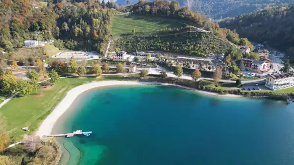 Vista aerea del lago di Ledro con spiaggia e campeggio. Un luogo ideale per il best Ledro camping, con acque cristalline e montagne verdi.